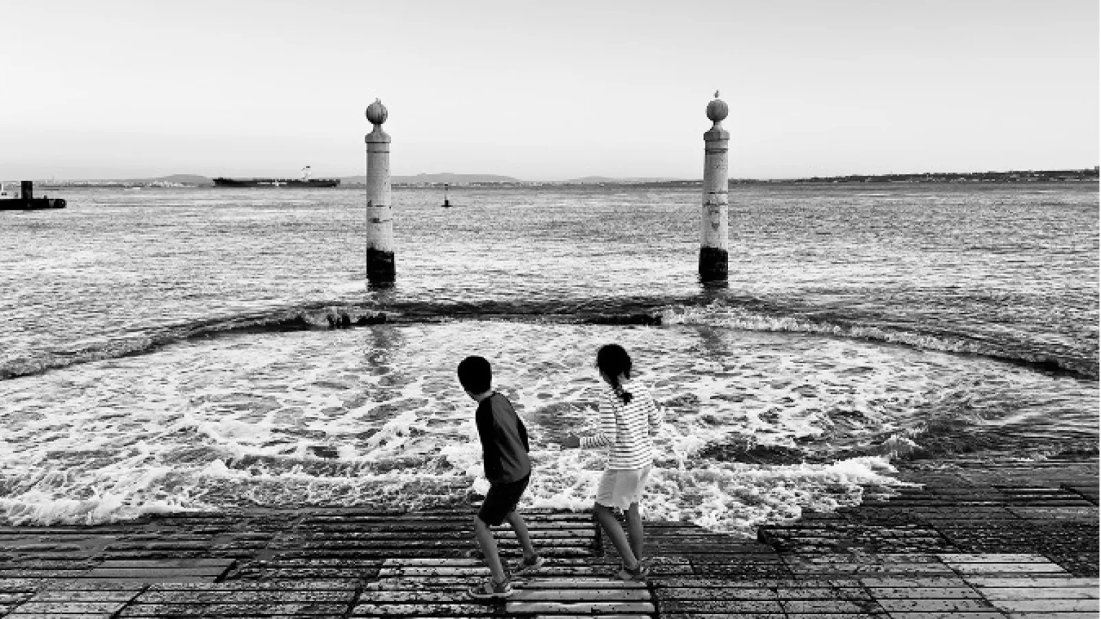 Two children standing near large body of water 