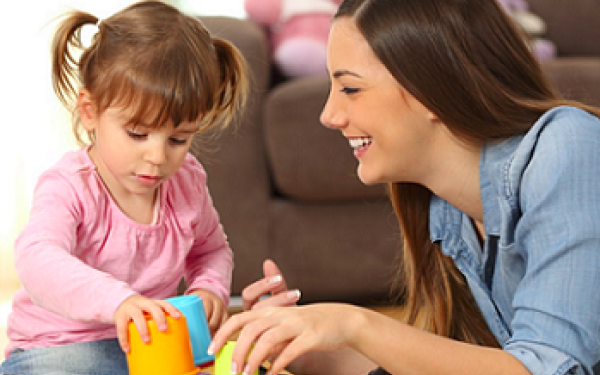 Psychology Professional smiling while helping a kid with blocks