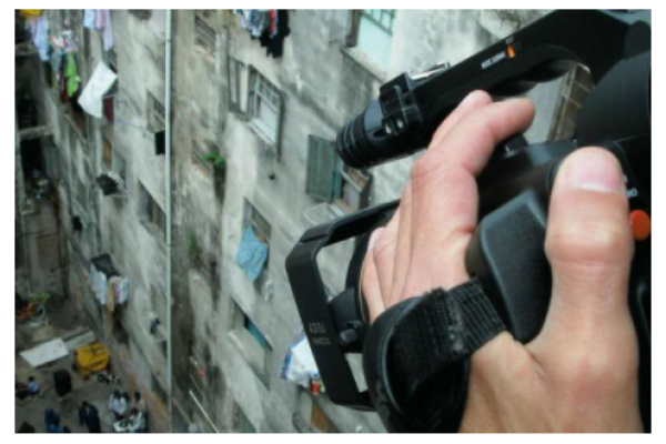 Man with video camera recording street from building