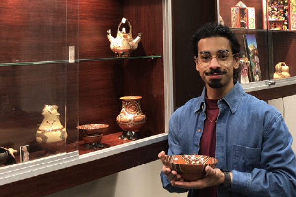 Brandon D'Souza with an artifact from the Andean and Amazonian Indigenous Art and Cultural Artifacts Collection