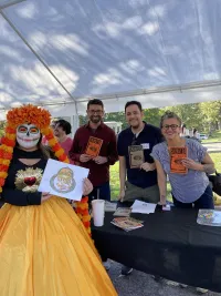 three people standing with a book